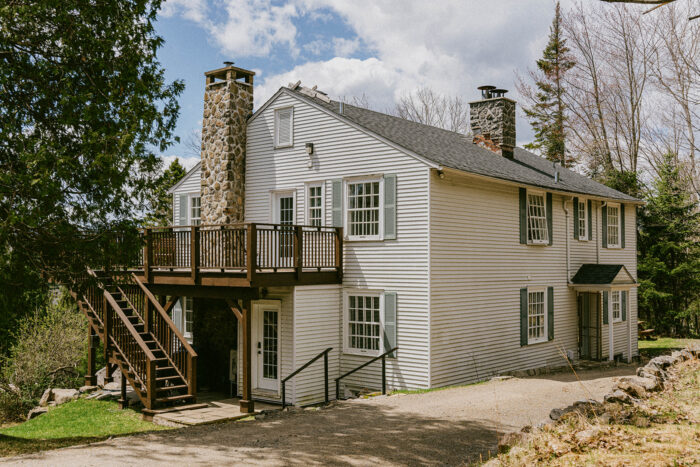 Maison du Havre du Rocher à Val-Morin, avec balcon et cheminée en pierre, entourée de nature dans les Laurentides.