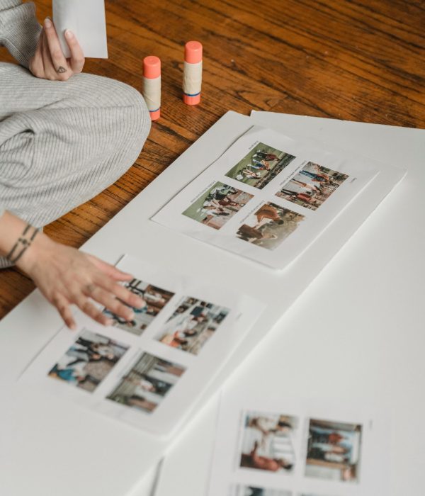 Atelier de collage créatif – Inspiration et expression personnelle Personne assise au sol réalisant un collage créatif avec photos imprimées et bâtons de colle.