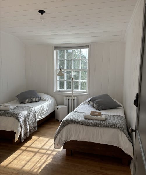 Chambre à occupation double avec deux lits simples, linge de lit gris et lumière naturelle au Havre du Rocher, Val-Morin.