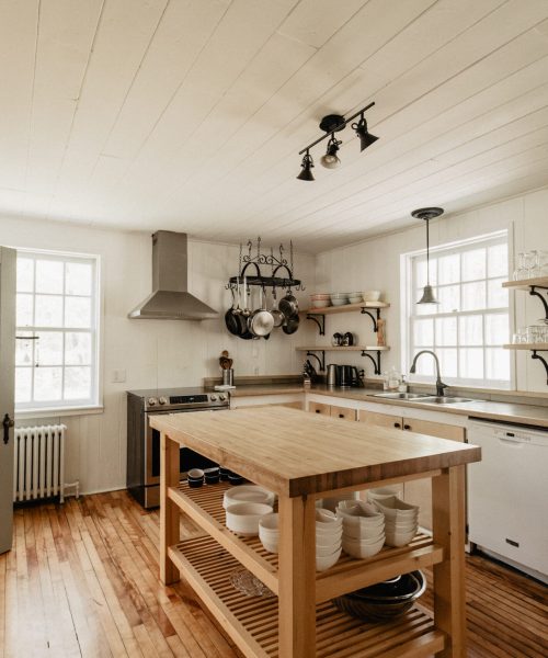 Cuisine spacieuse et lumineuse avec îlot central, étagères ouvertes et vaisselle prête à l’emploi au Havre du Rocher, Val-Morin.