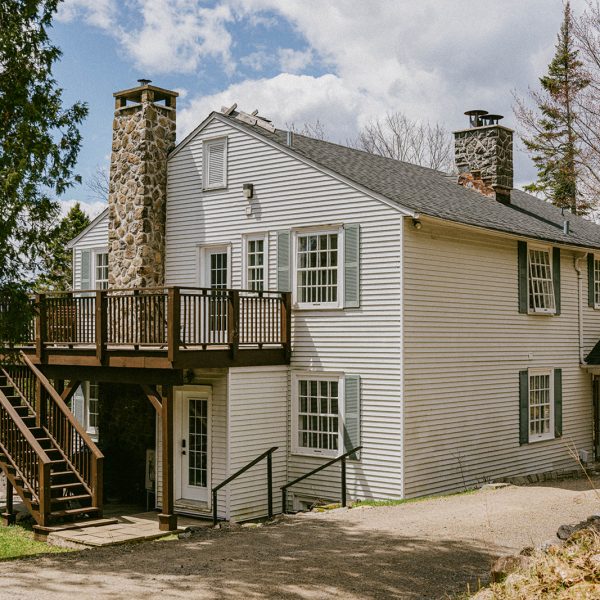 Le couvent Val-Morin Maison du Havre du Rocher à Val-Morin, avec balcon et cheminée en pierre, entourée de nature dans les Laurentides.